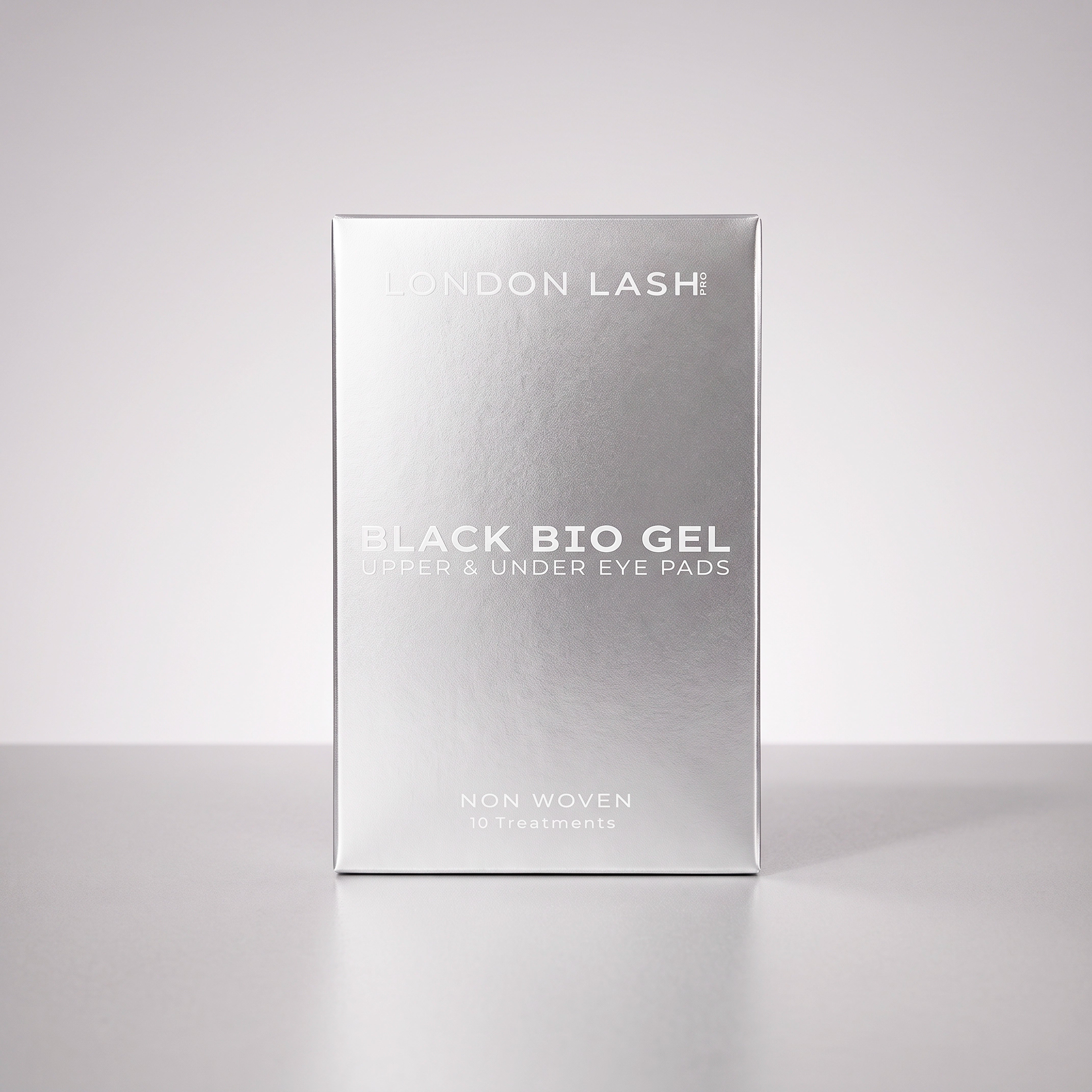 Vista frontal de la caja metálica plateada de los parches negros de biogel para párpados superiores y contorno de ojos de London Lash sobre un fondo liso de estudio.